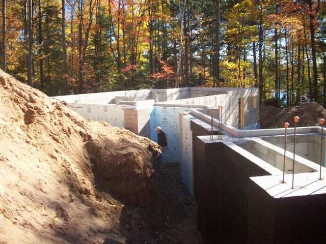 9' wall with 4" brickledge; Large stone column supports; Waterproofed to top of wall; 2" styrofoam being installed.